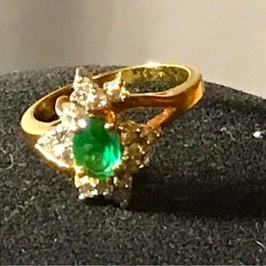 Gold ring with emerald center stone and round diamonds around